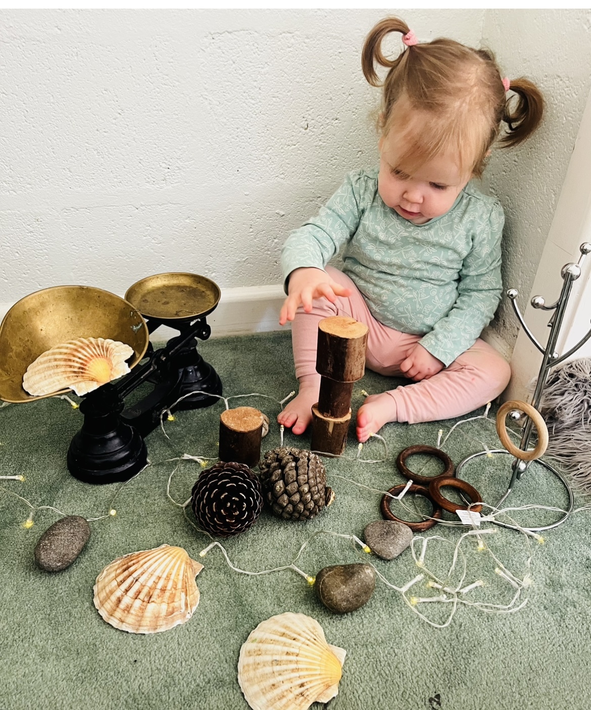 A child stacking log slices and pine cones